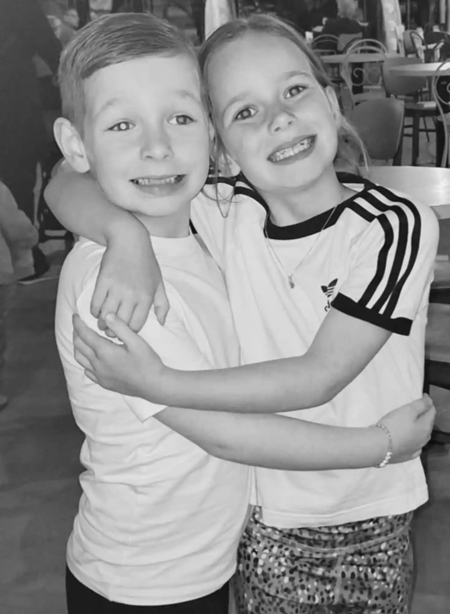 Twee lachende kinderen die elkaar omarmen.